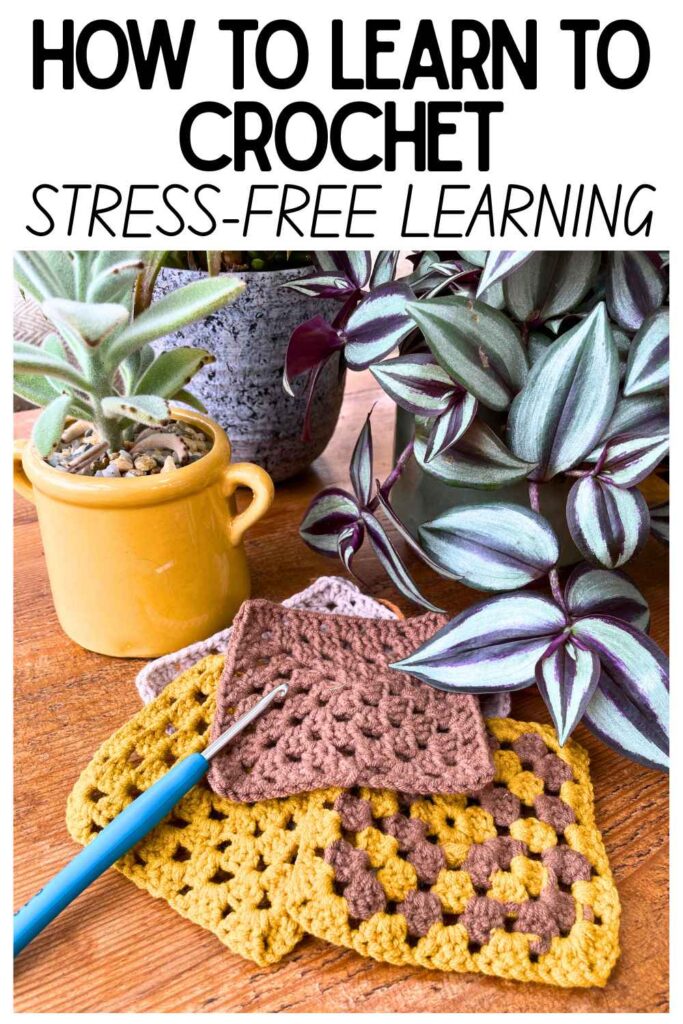 photo of a crochet hook on some granny squares on a table in front of some pot plants