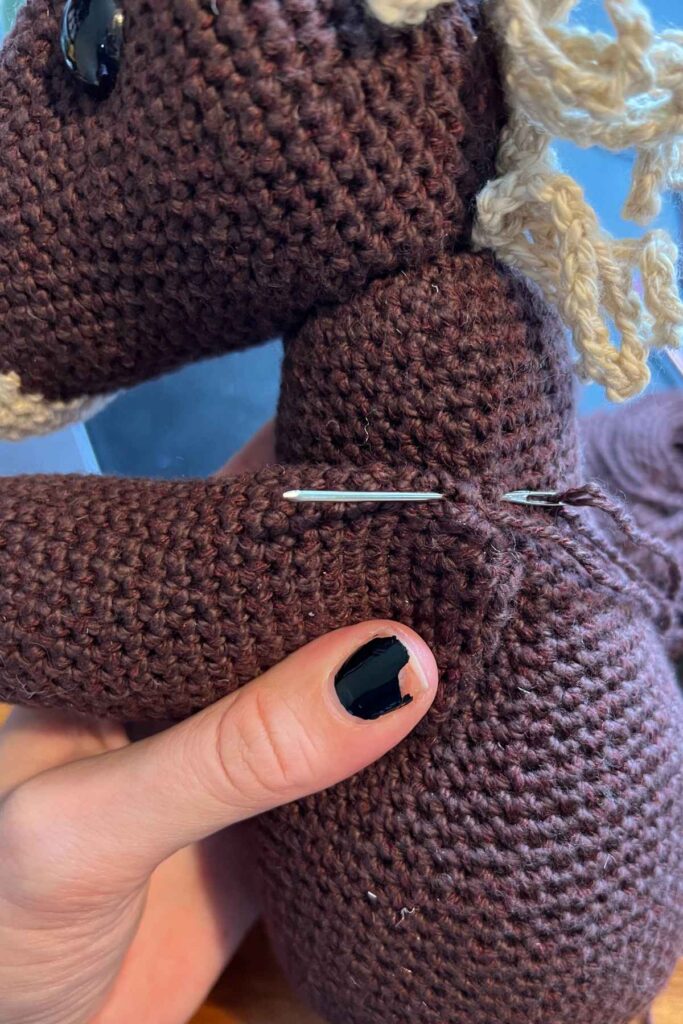 image showing the crochet horse's arms being sewn on