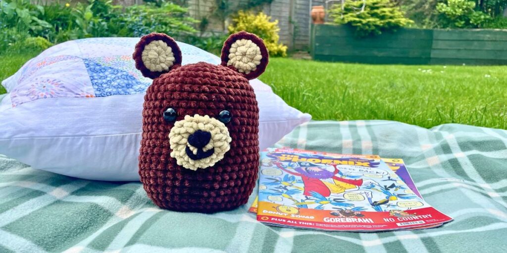image of the crochet teddy bear on a picnic blanket