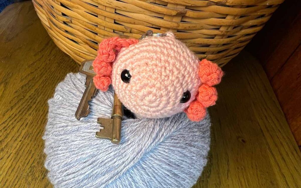 picture of the amigurumi axolotl keychain on some yarn