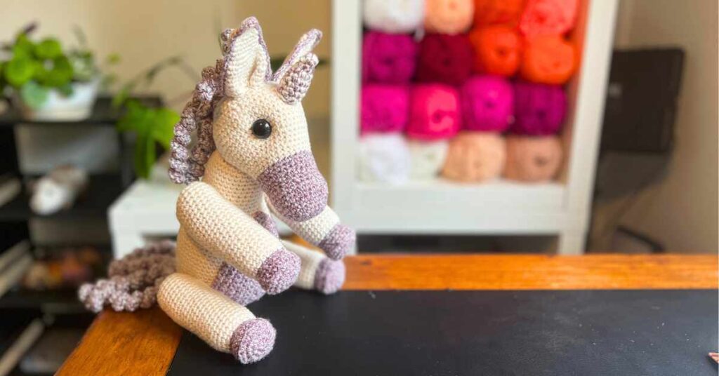 picture of my crochet unicorn in front of my yarn