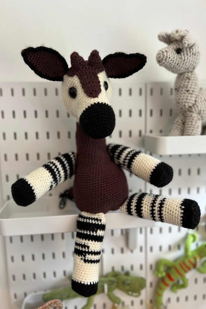 photo of my crochet okapi sitting on my peg board shelf