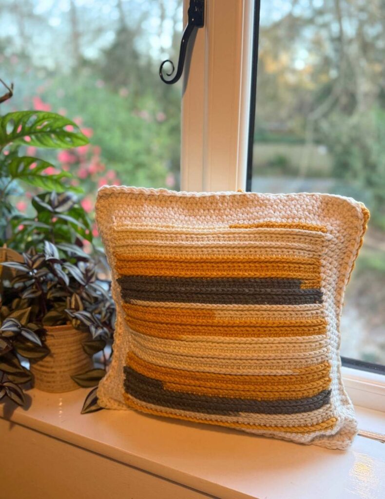 front side of camel stitch pillow in the window