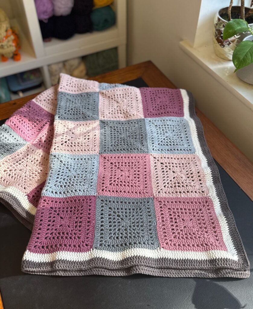 pink crochet blanket folded and laid out on my desk